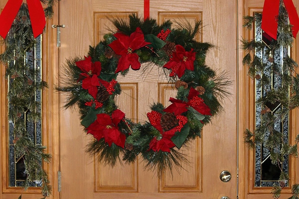 As guirlandas e as fitas vermelhas são elementos clássicos para decorar a porta durante o Natal...
