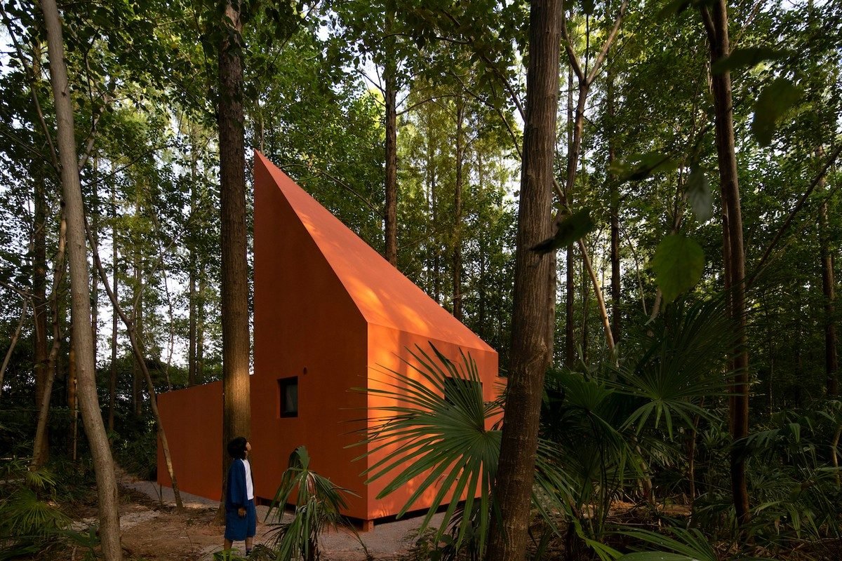 A casa Red Windmill traz uma paleta de tons vermelhos vibrantes, destacando-se em meio ao verde d...